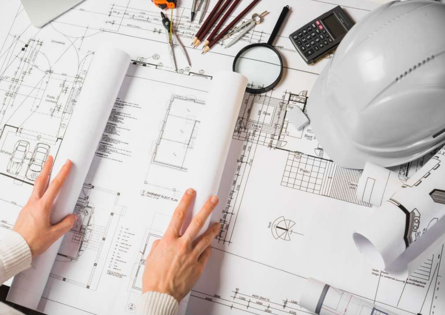 Architectural plans, drawing instruments and a safety helmet on a planning table